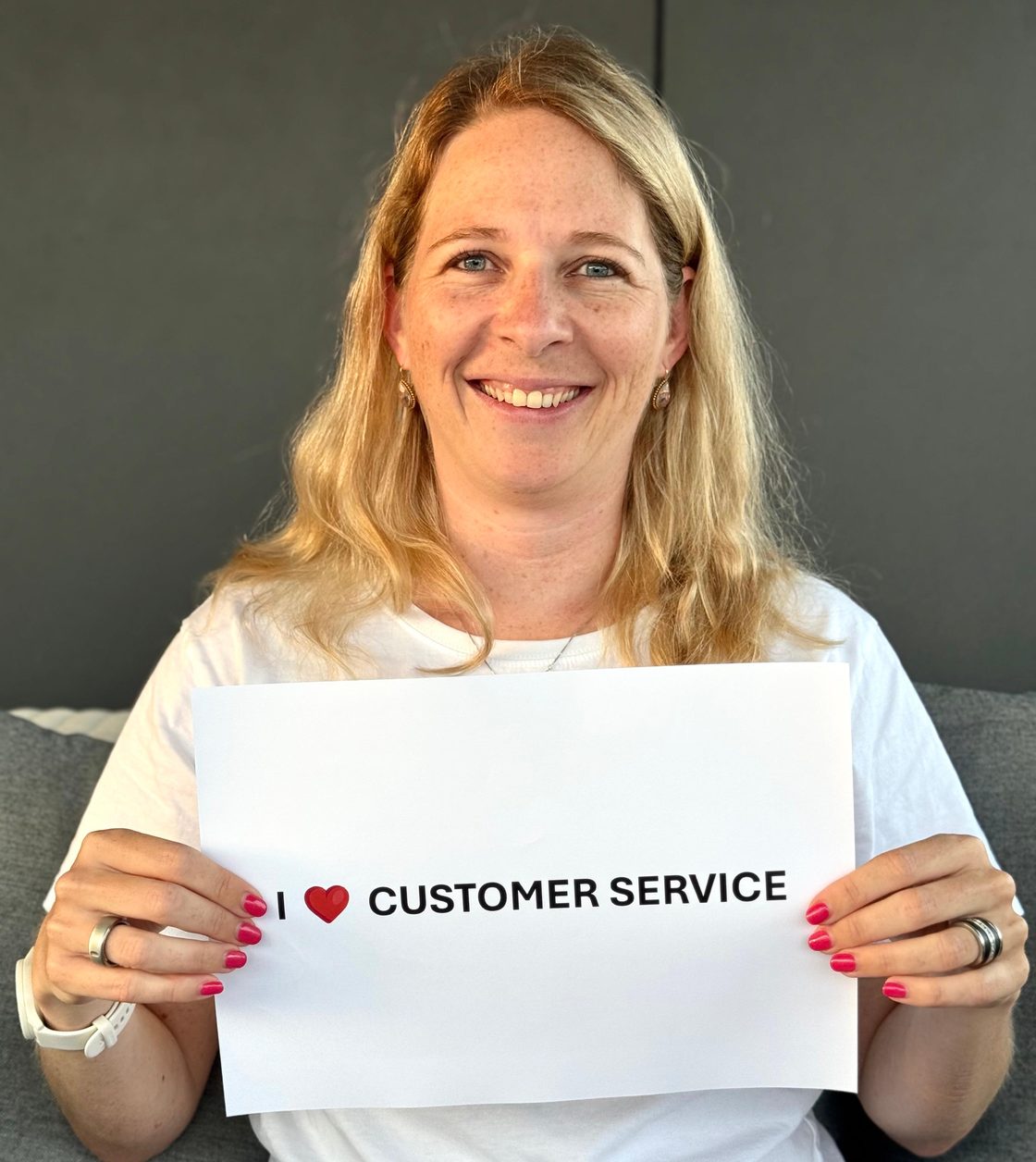 Fabienne Schuler, smiling, holding a sign that reads: I love customer service.
